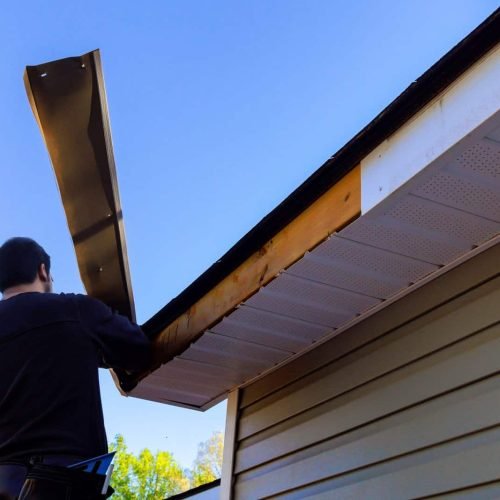 Master makes repairs after hurricane has caused aluminum fascia trim to blow off, exposing exposed wood