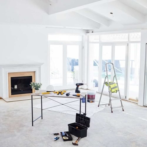 Shot of building plans and equipment on a table in an empty living room during the day.